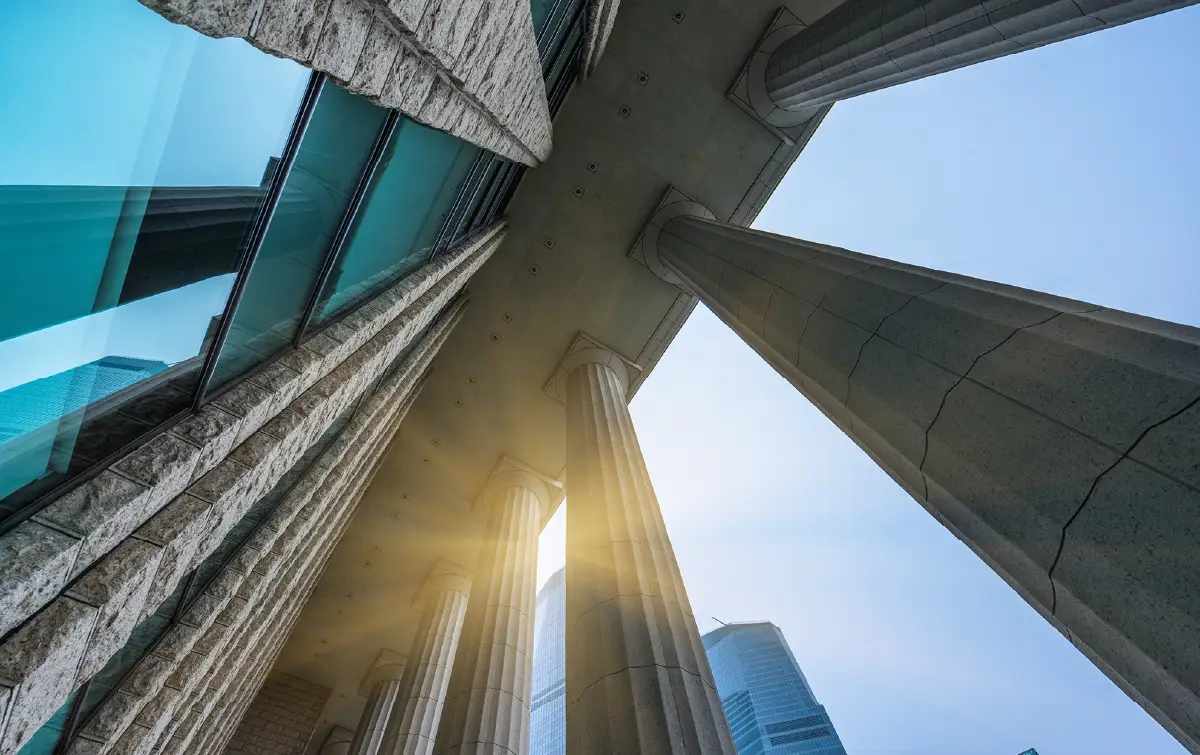 Upward view of modern government-style office buildings and columns against the sky, representing digital modernization and public sector infrastructure.